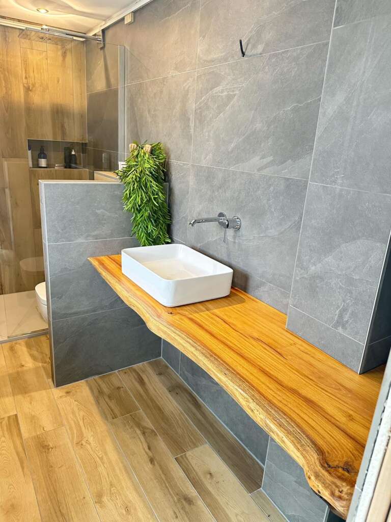 Plan vasque en bois massif à bord naturel dans une salle de bain au carrelage gris