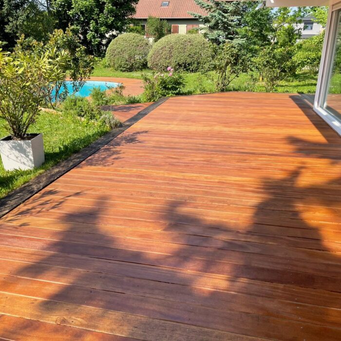 Terrasse en lames de bois le long d’une maison, avec jardin et piscine