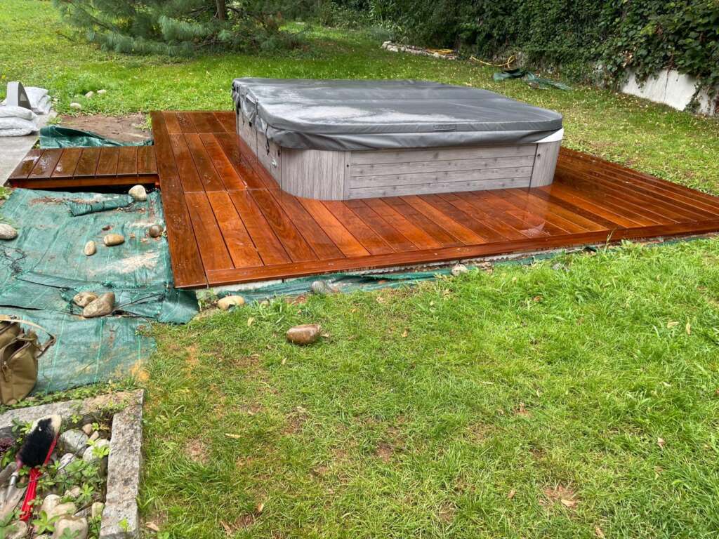Plateforme en lames de bois accueillant un spa, dans un jardin