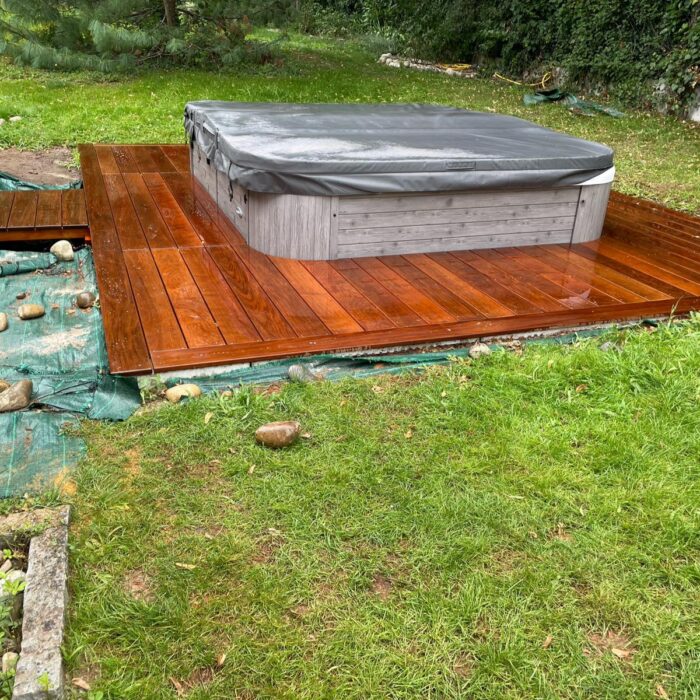 Plateforme en lames de bois accueillant un spa, dans un jardin